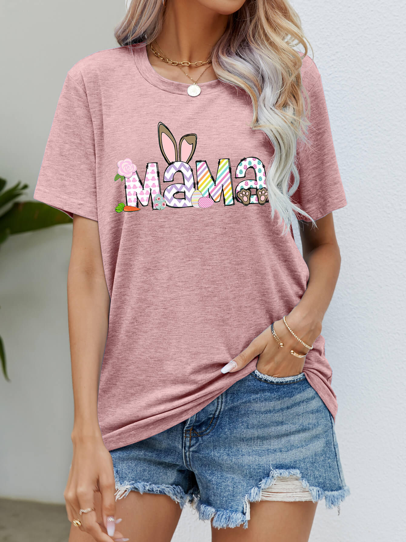 Dusty Pink graphic tee with Easter Mama text, bunny ears, and colorful patterns.