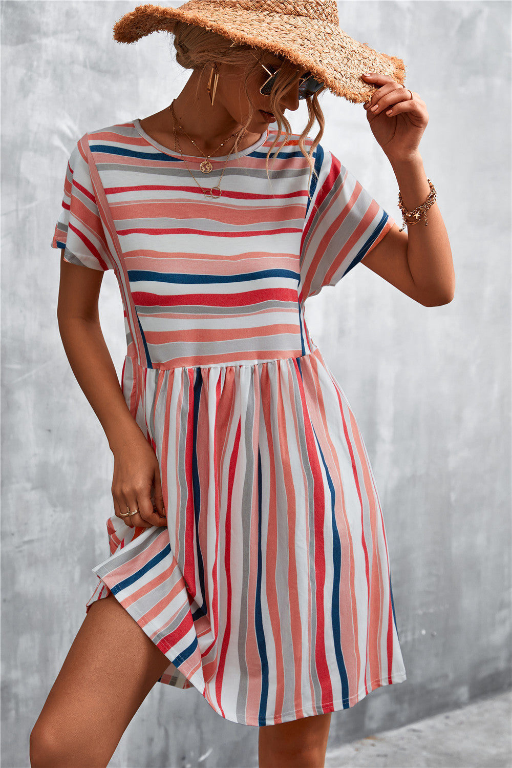 Striped trapeze dress with short sleeves and a yoke seam in coral, navy, and grey stripes.