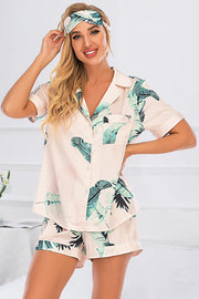 Botanical print satin pajama set in blush pink with short sleeves, button front, and matching shorts.