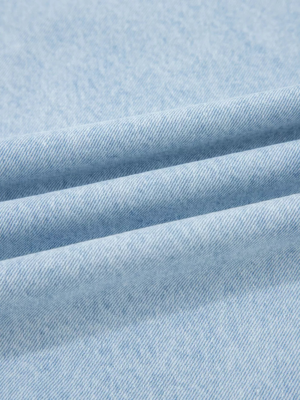 Light wash denim fabric detail, showing texture and weave of wide-leg jeans.