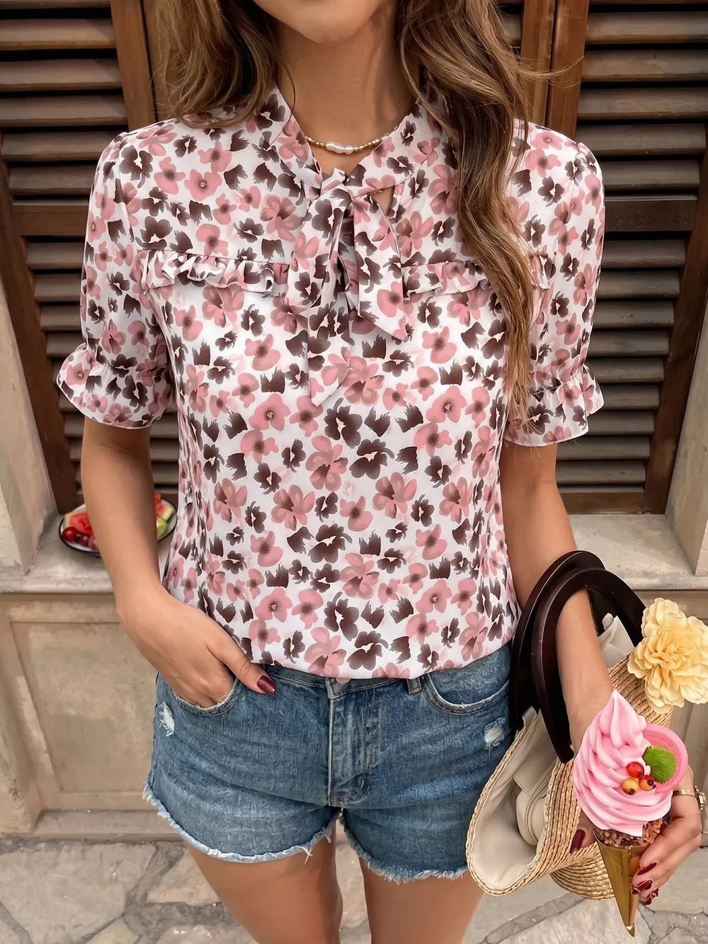 Floral tie-neck ruffle shirt with short puff sleeves and a pink floral print.
