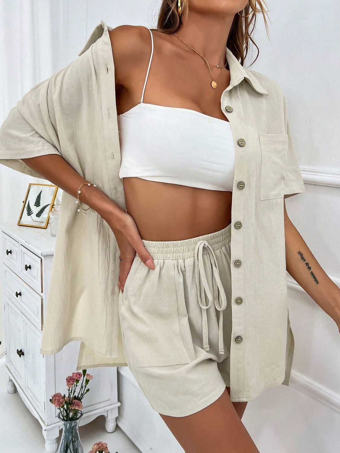 Linen resort shirt and shorts set in a light beige color with button details and drawstring waist.