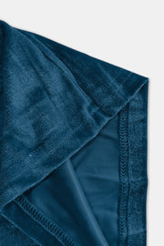 Plush velvet wide-leg trousers in deep teal showing fabric texture and stitching detail.