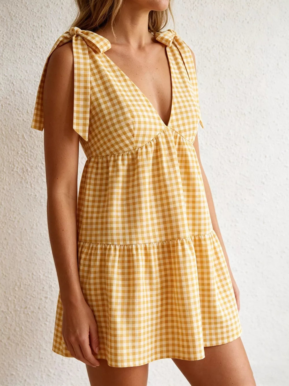 Yellow gingham mini dress with tie straps and a tiered skirt.