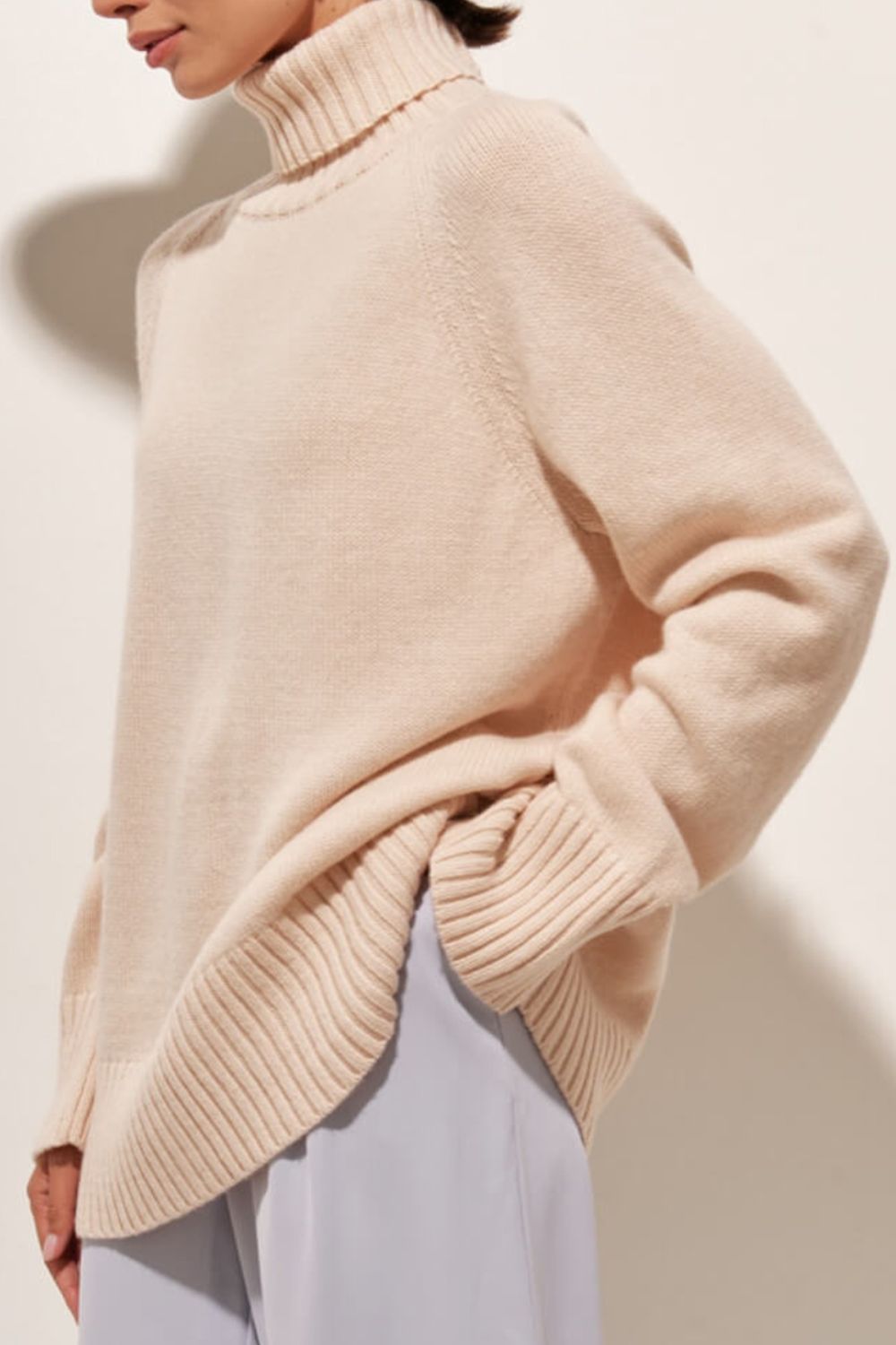 Blush pink cashmere turtleneck sweater with raglan sleeves and ribbed details.