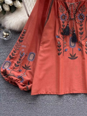 Orange Red embroidered tie neck blouse with billowy sleeves and floral detail.