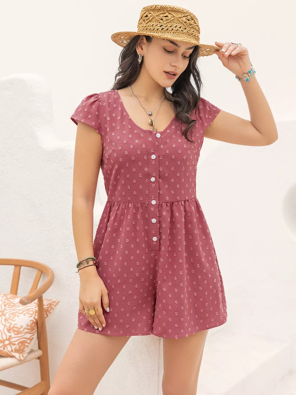 Maternity romper in rose with white swiss dots, V-neck, cap sleeves, and button front.