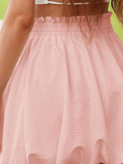 Blush pink bubble hem mini skirt with smocked waist and textured fabric.