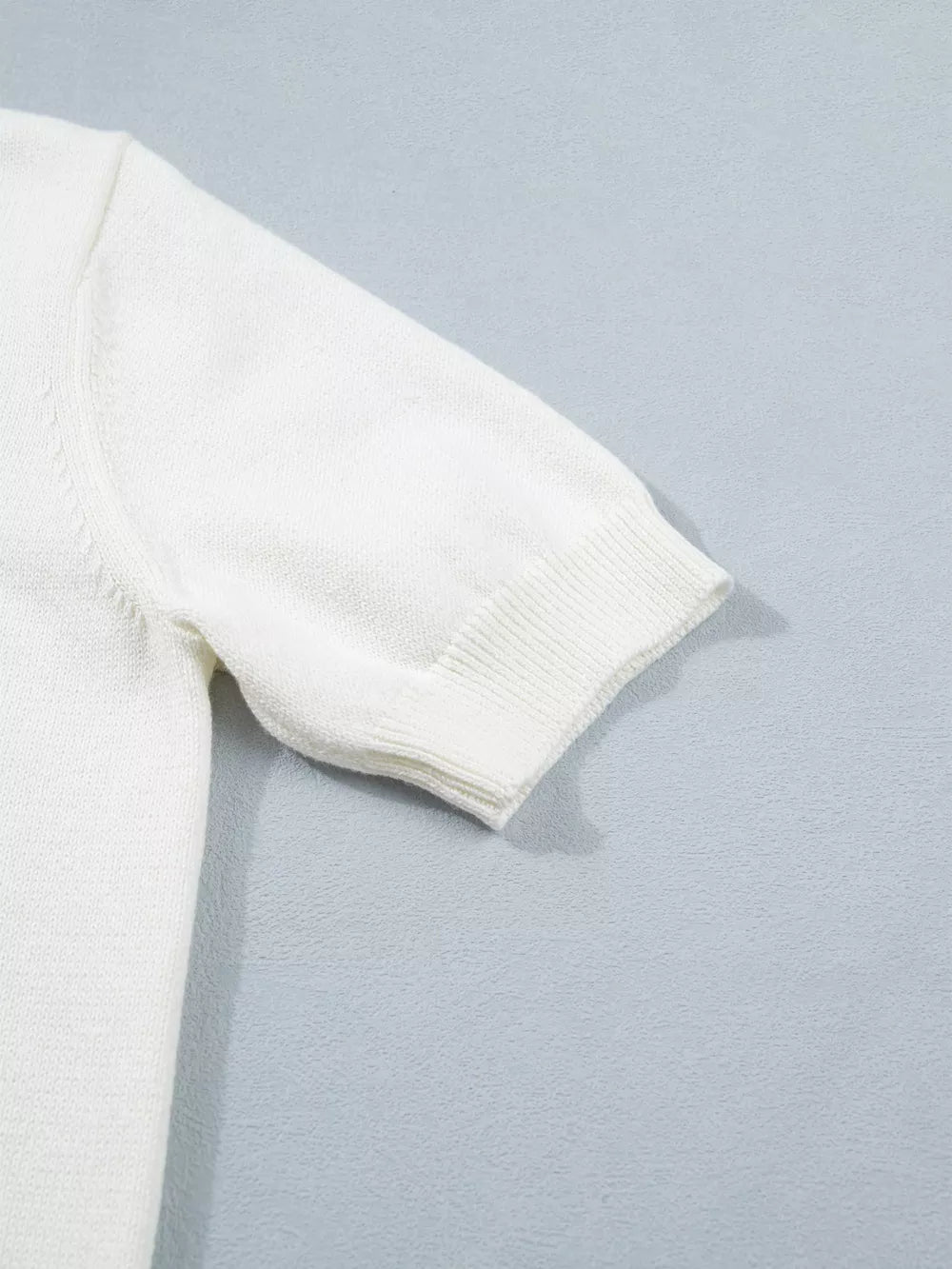 White short-sleeve sweater with ribbed cuffs and hem, made of acrylic and cotton blend.