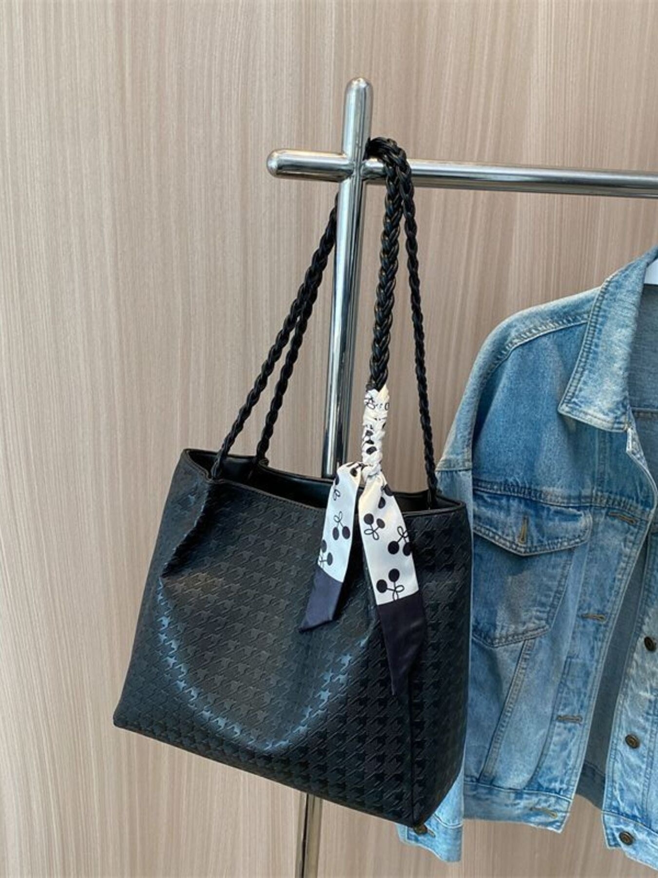 Black shopper bag with braided handles and a cherry print scarf detail.