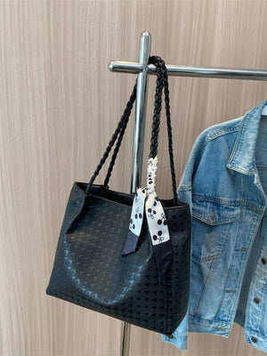 Black shopper bag with braided handles and a cherry print scarf detail.