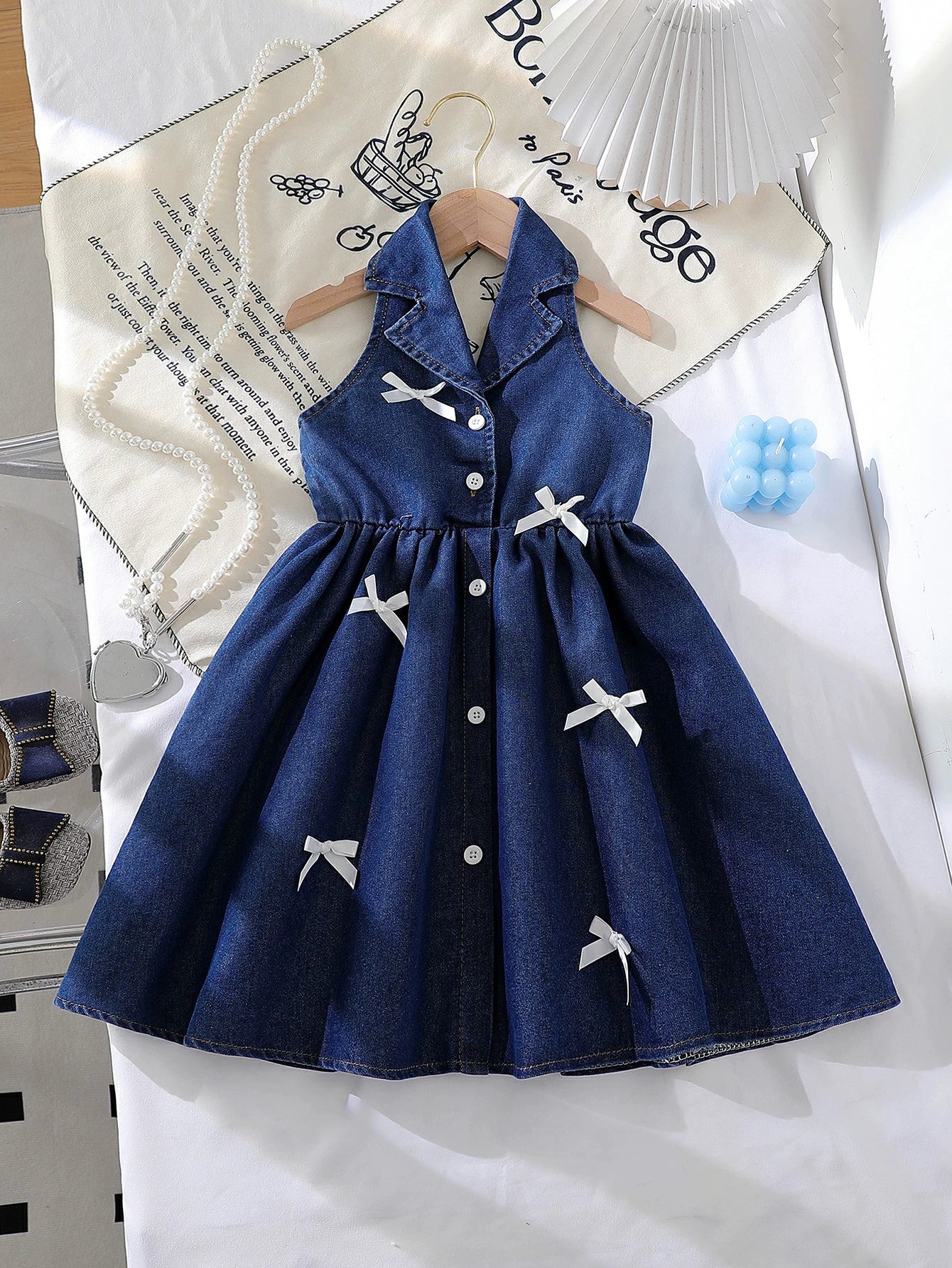 Dark blue denim baby dress with white bowknot details and button-down front.