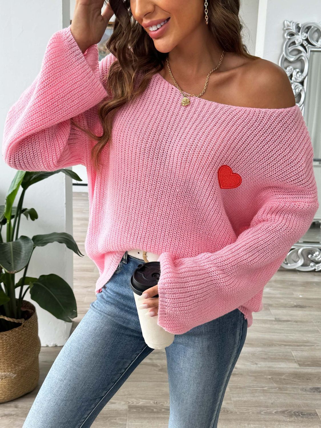 Pink slouchy boatneck knit sweater with embroidered red heart detail.
