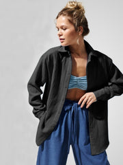 Black textured cotton overshirt with relaxed fit and button front, styled open over a blue bralette.