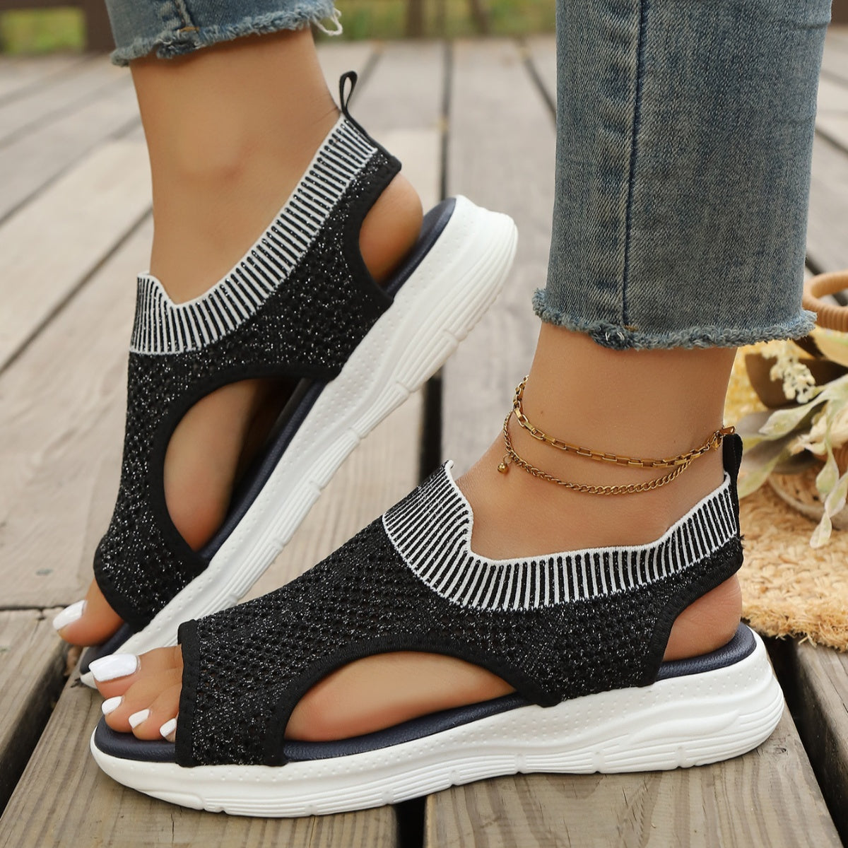 Black open-toe sandals with white striped ankle cuff and white sole.