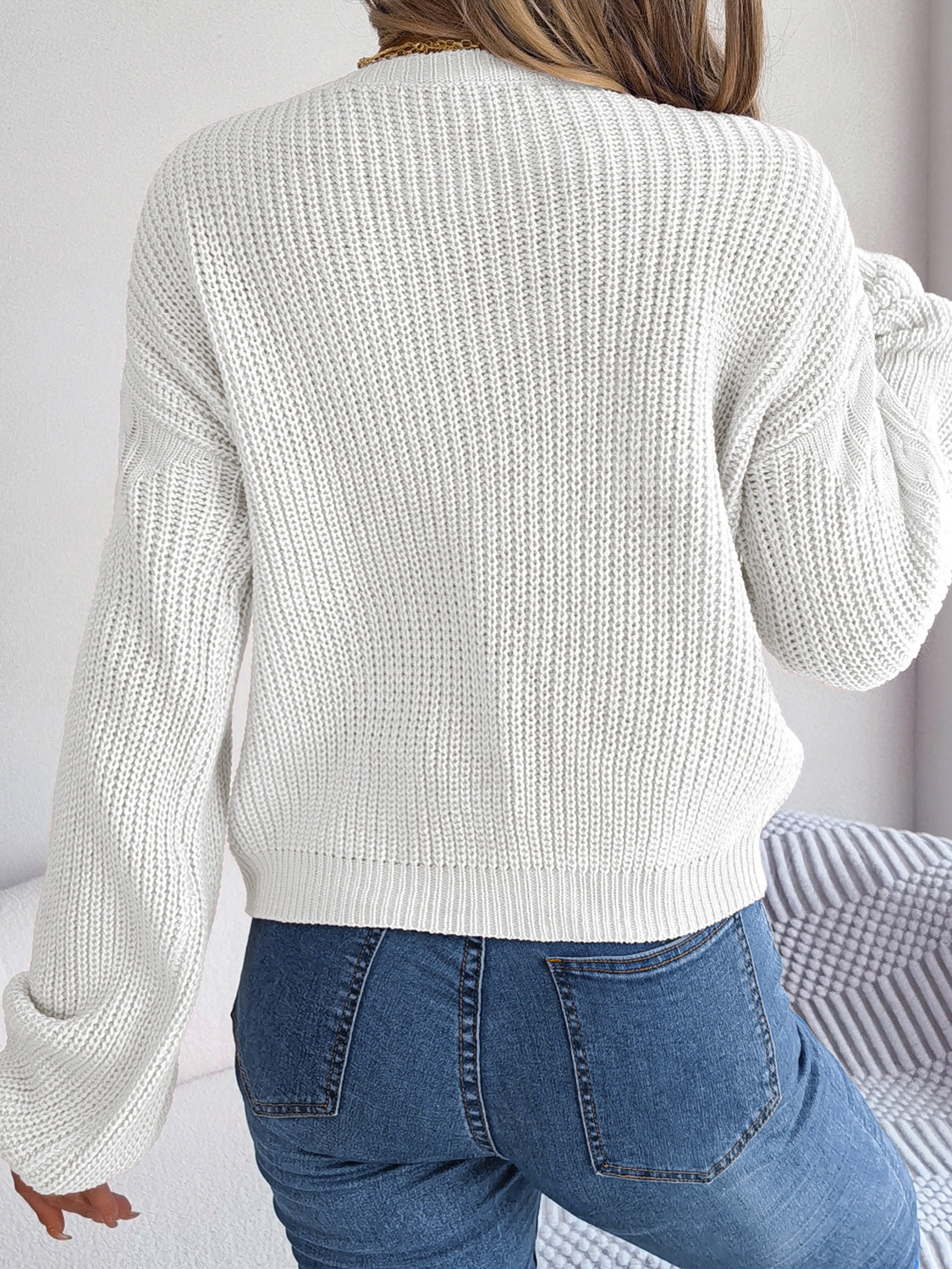 White cable knit drop shoulder pullover sweater with balloon sleeves.