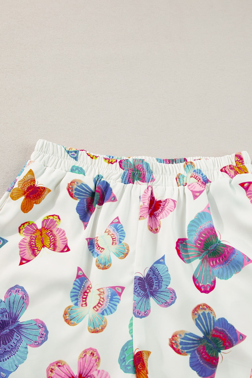 White pajama shorts with colorful butterfly print and elastic waistband.