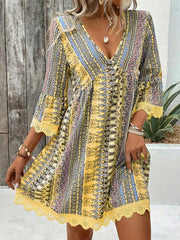Yellow bohemian v-neck dress with bell sleeves, lace trim, and colorful print.