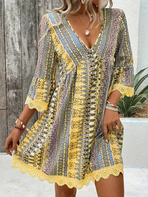 Yellow bohemian v-neck dress with bell sleeves, lace trim, and colorful print.