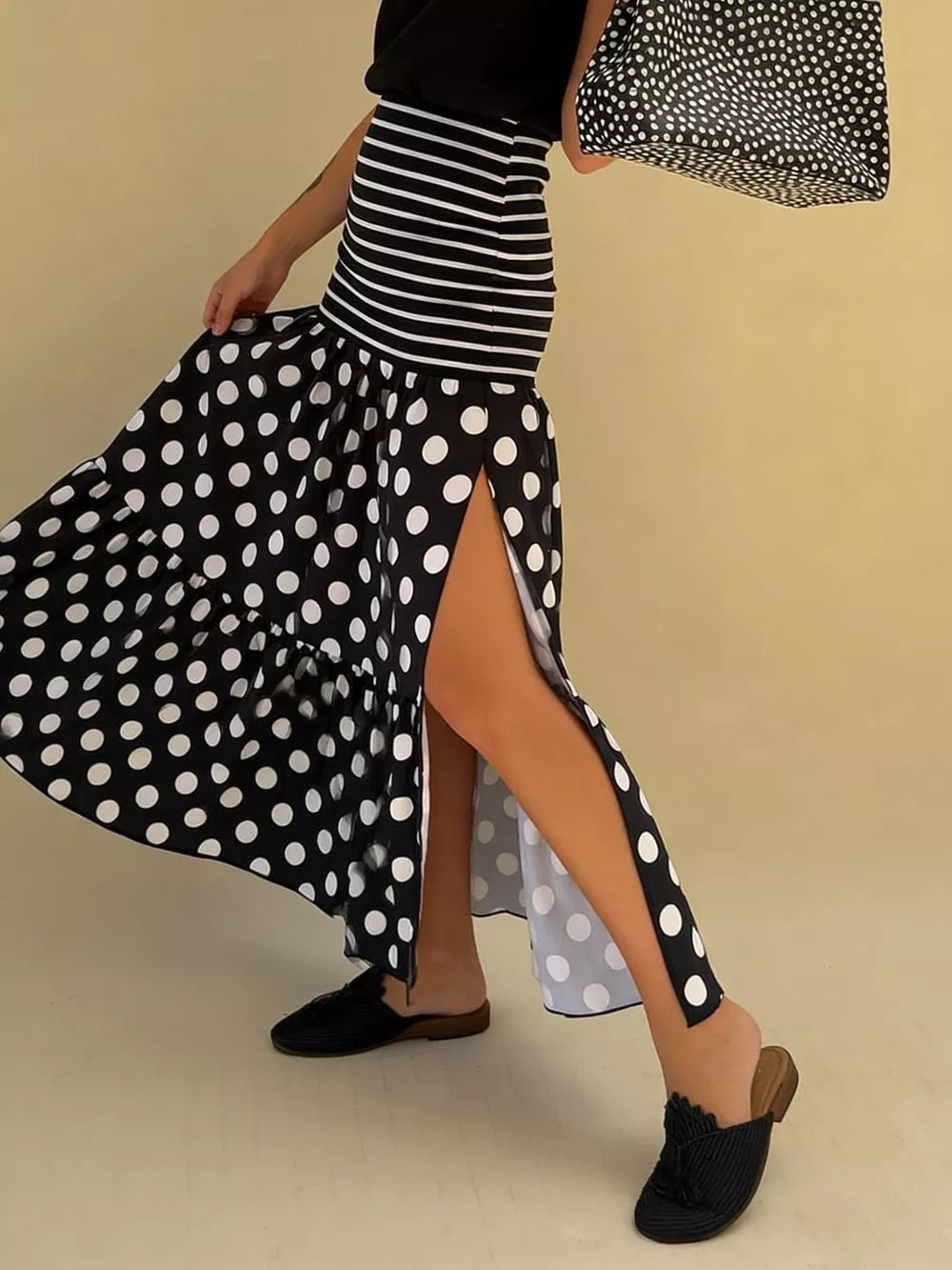 Black polka dot maxi skirt with high slits and ruffled hem, paired with a striped top.