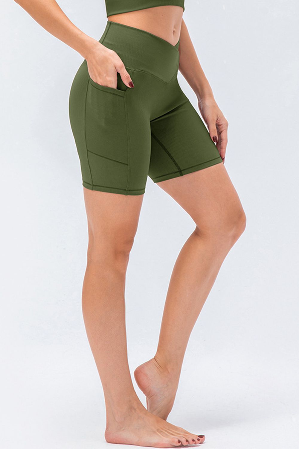 Cross-waist bike shorts in Matcha Green with side pockets and a textured ribbed fabric.