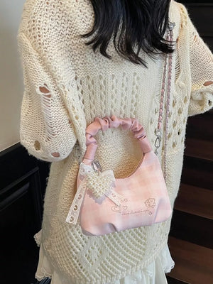 Charming mini crossbody bag in blush pink with ruched handle and pearl bow charm.