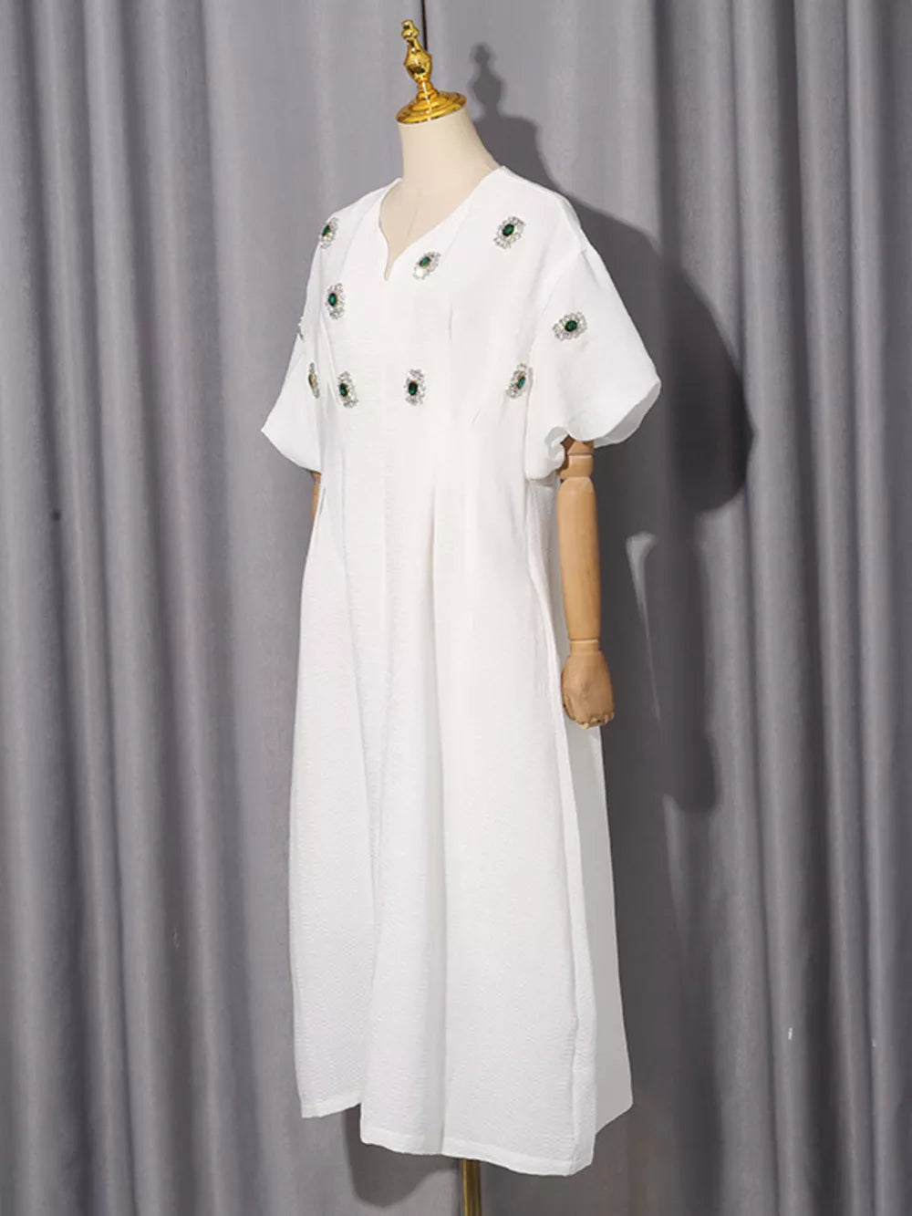 White midi dress with V-neck, puff sleeves, and scattered green rhinestone embellishments.