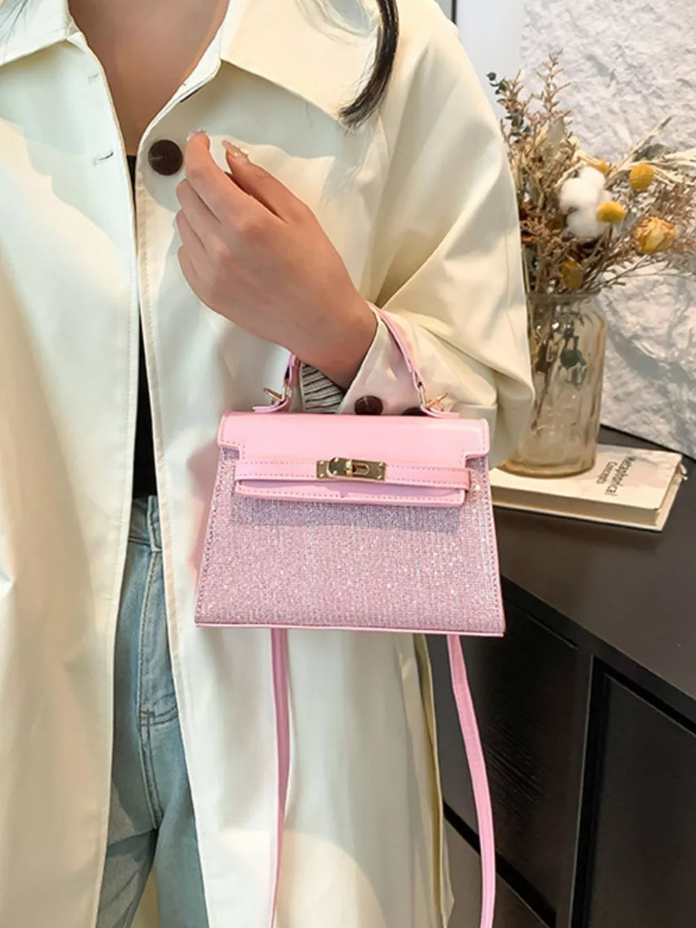 Pink glitter textured mini crossbody bag with gold hardware and a top handle.