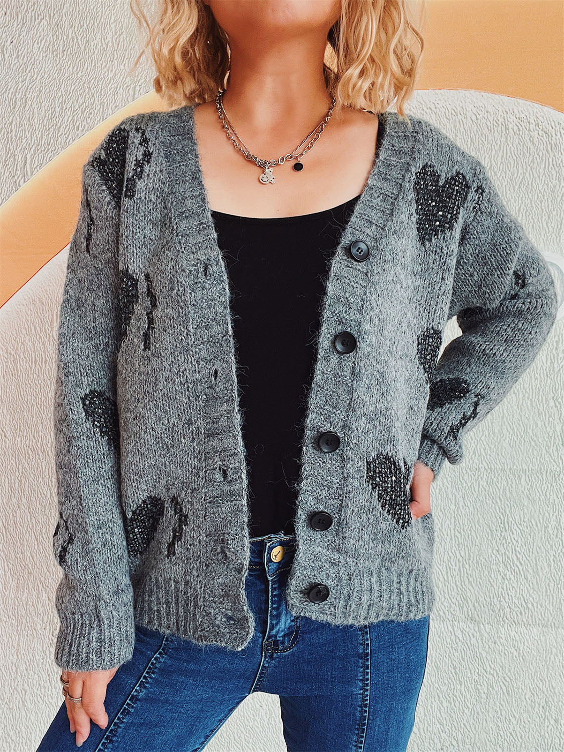 Dark gray acrylic knit cardigan with black heart motif, button front, and V-neck.