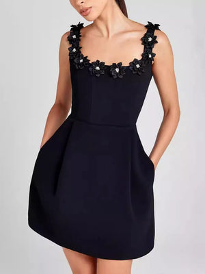 Black mini dress with floral embellishments on the neckline and pockets.