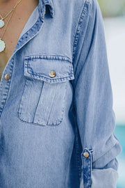Relaxed light blue denim shirt with buttoned patch pockets and rolled sleeves.