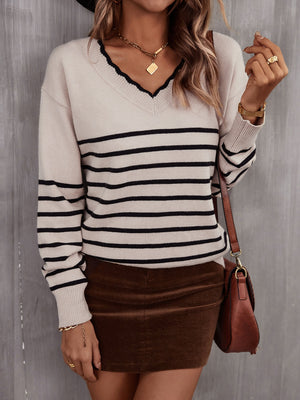 Beige knit sweater with black stripes, V-neck, and scalloped trim.