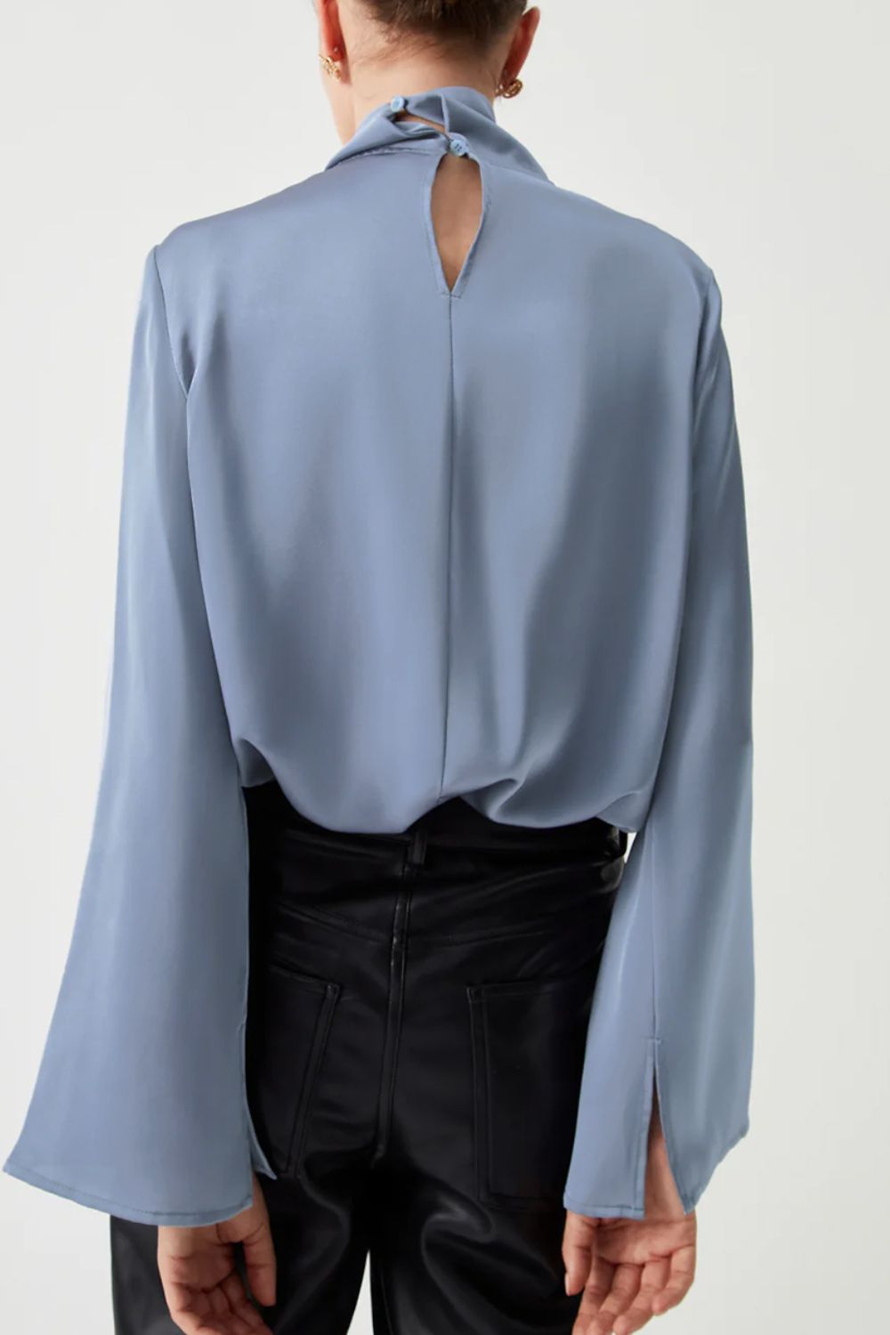 Dusty blue blouse with draped neckline, bell sleeves, and keyhole back detail.