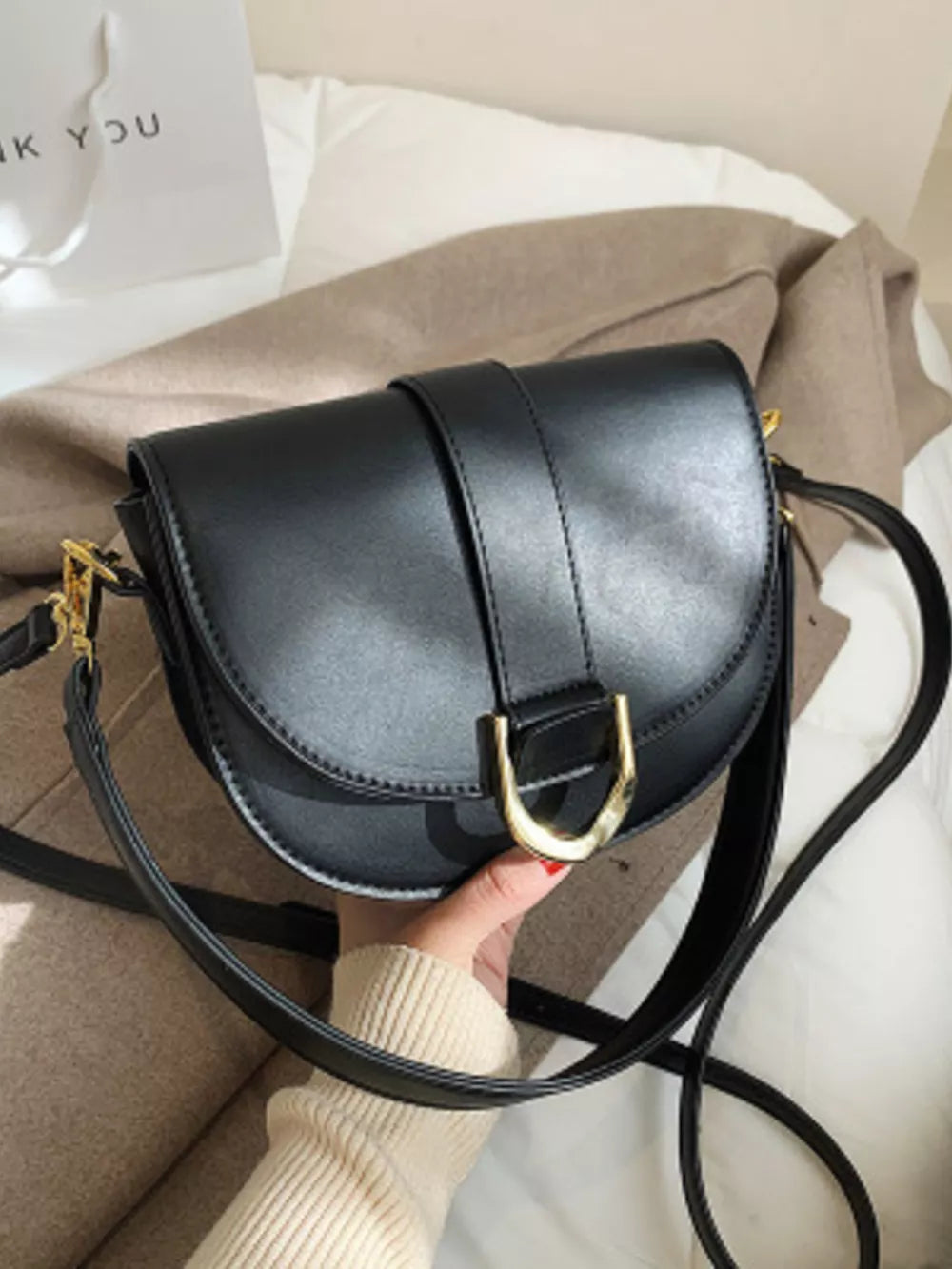 Chic black semi-circular flap crossbody bag with gold hardware detail.