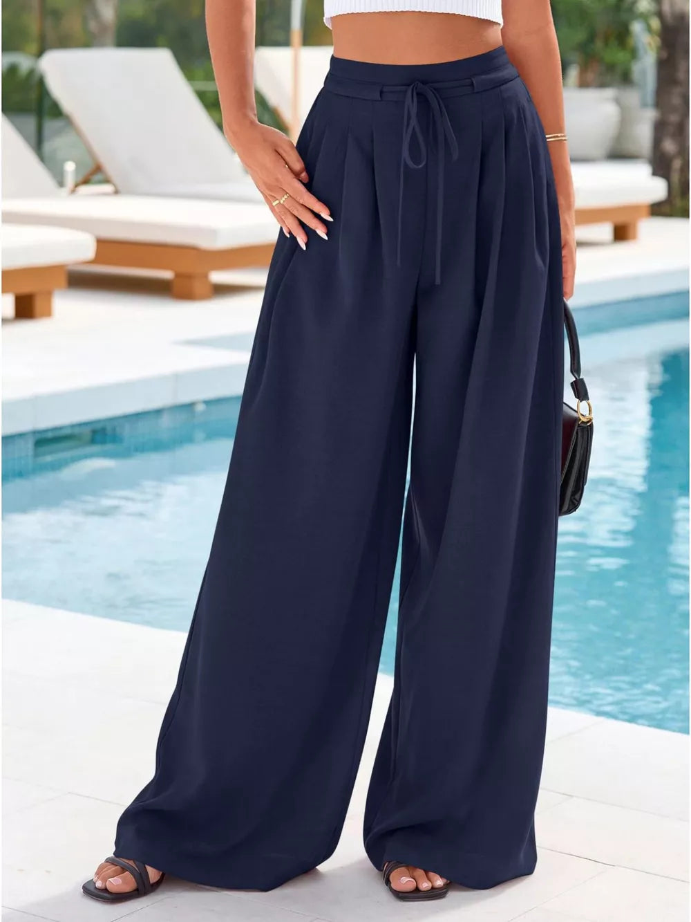 Dark blue high-waisted pleated wide-leg pants with drawstring and pockets.