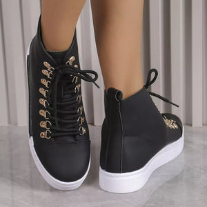 Black lace-up platform sneakers with gold D-ring eyelets and white soles.