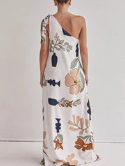 White one-shoulder maxi dress with floral and vase print, tie detail.