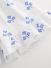 White cotton toddler set with blue floral print and ruffled hem.
