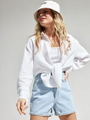 White textured cotton overshirt with relaxed fit, tied at waist, worn over tank top.