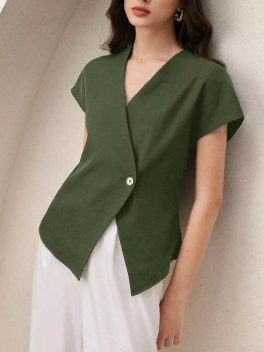 Green asymmetrical wrap shirt with cap sleeves and a single button detail.