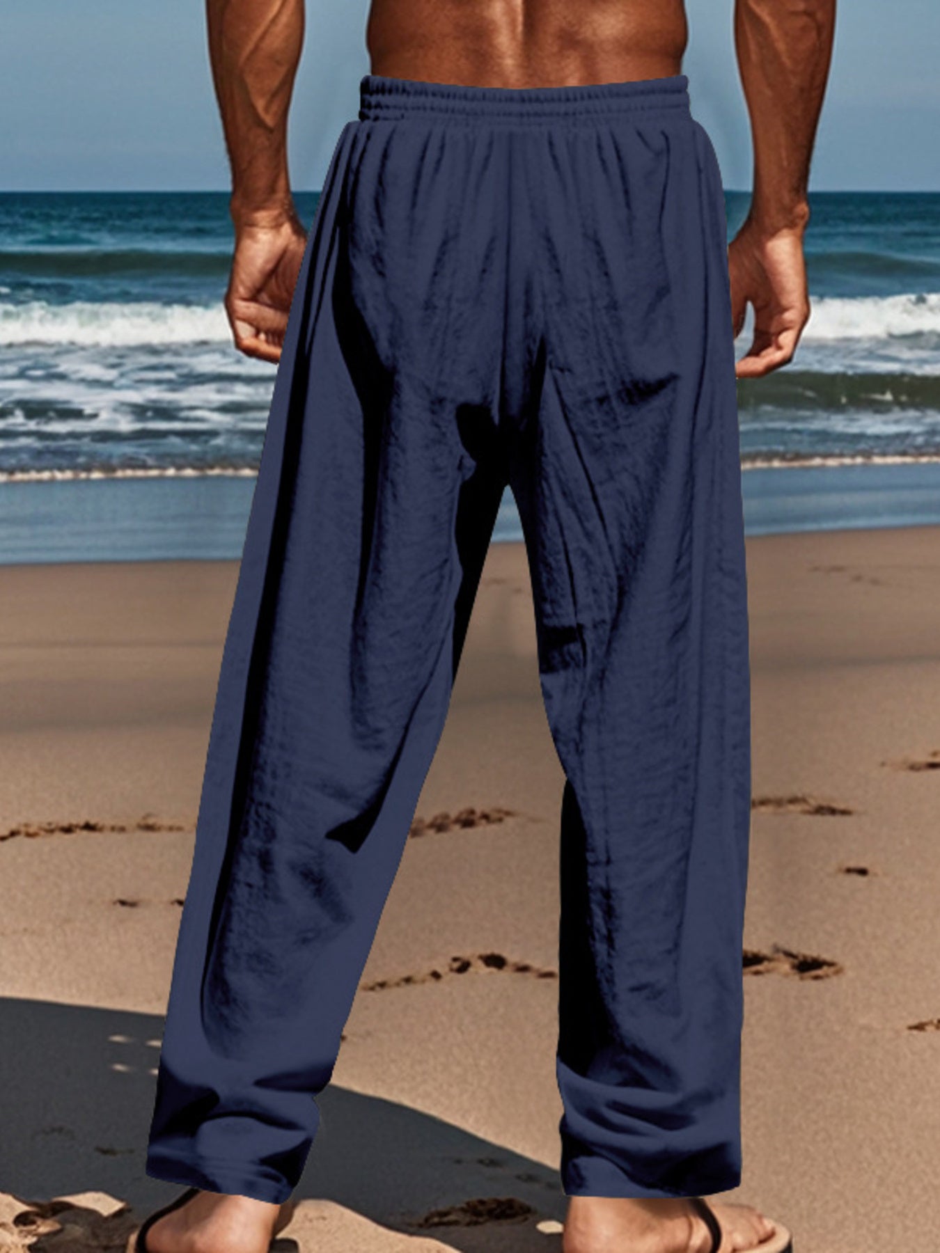 Navy blue relaxed fit drawstring sweatpants with button-fly on a man at the beach