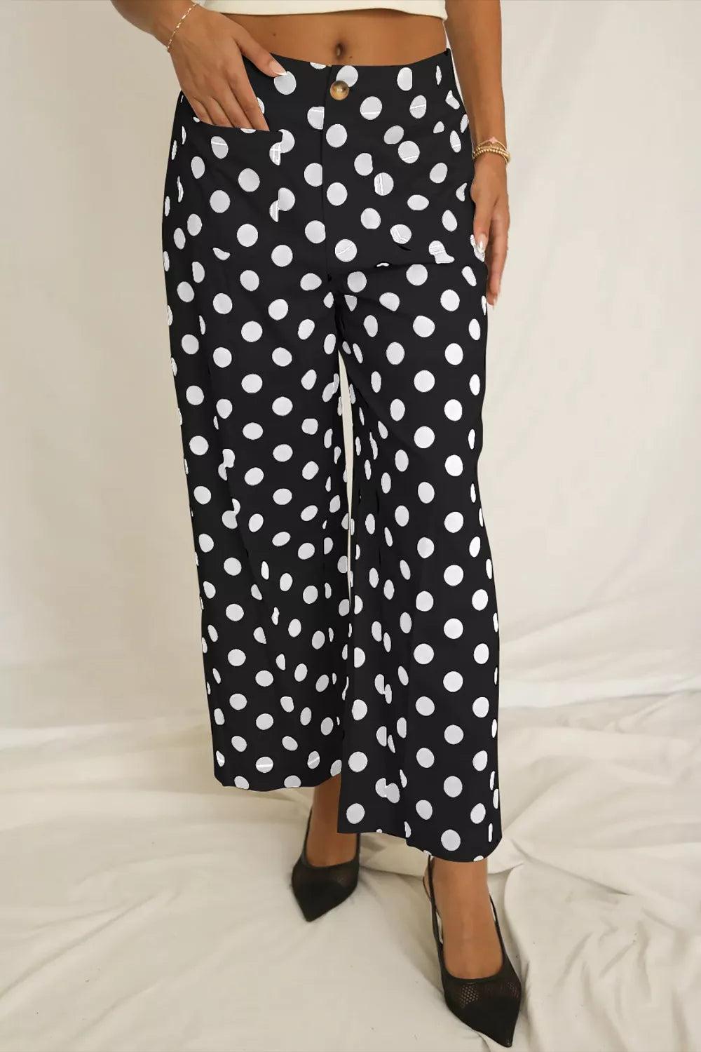 Black polka dot mid-rise trousers with pockets and a button closure.