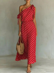 Red polka dot one-shoulder maxi dress with cinched waist and tie details.