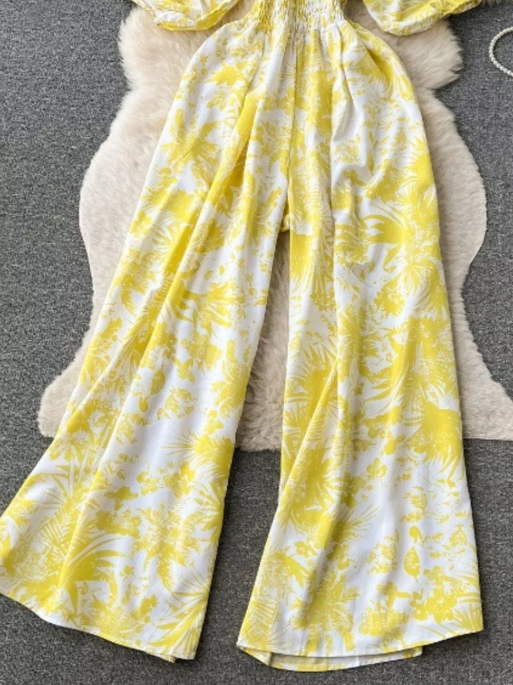 Yellow tropical print smocked wide-leg romper with puff sleeves