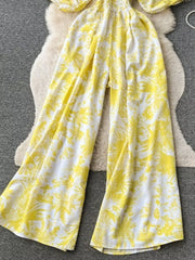 Yellow tropical print smocked wide-leg romper with puff sleeves