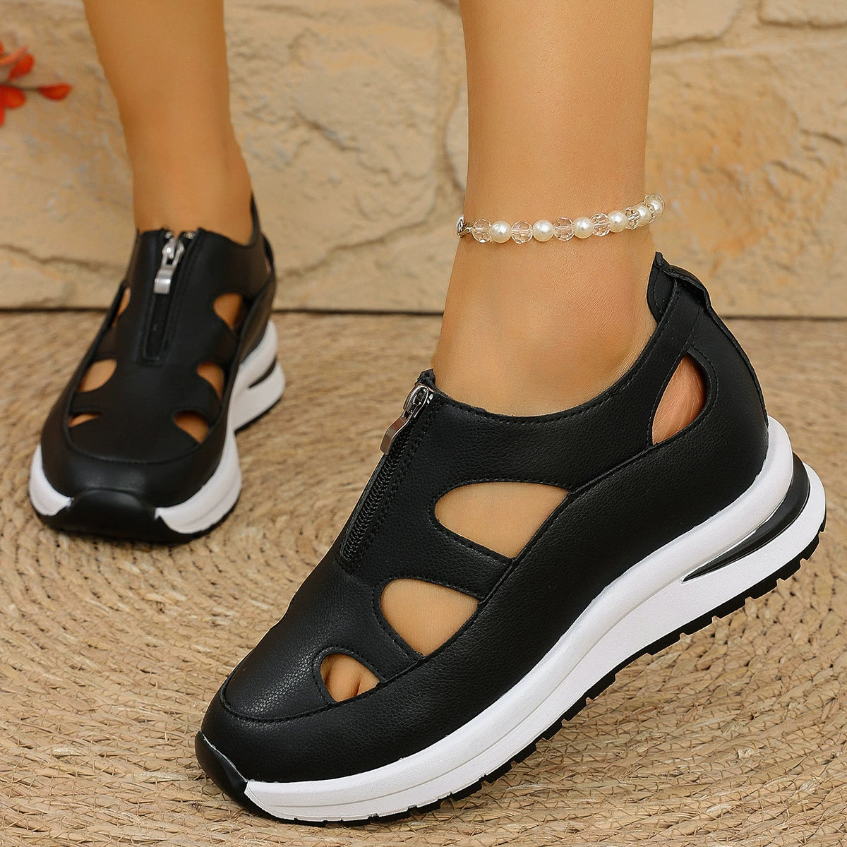 Black cutout wedge sneakers with zipper and chunky white sole.