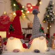 Illuminated knit gnomes in deep red and light gray with pom-pom hats and striped sleeves.