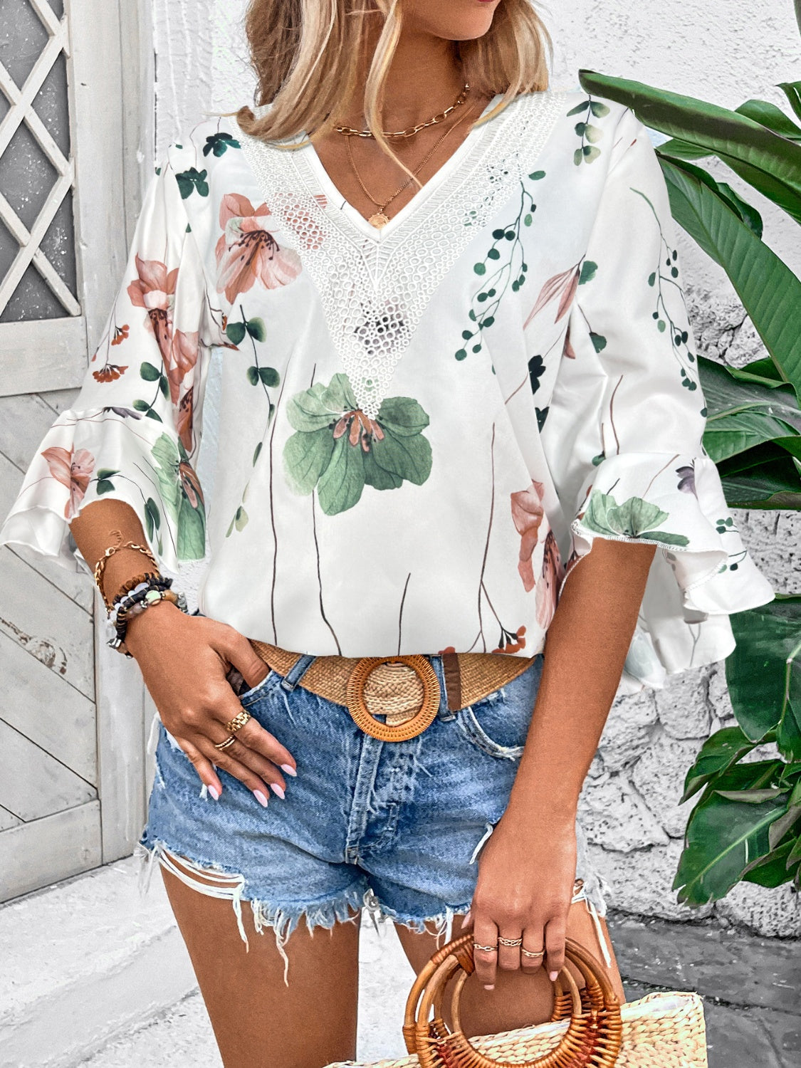 White floral bell sleeve blouse with lace trim neckline and ruffled cuffs.