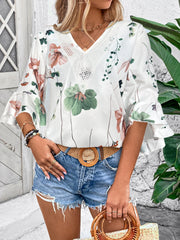 White floral bell sleeve blouse with lace trim neckline and ruffled cuffs.