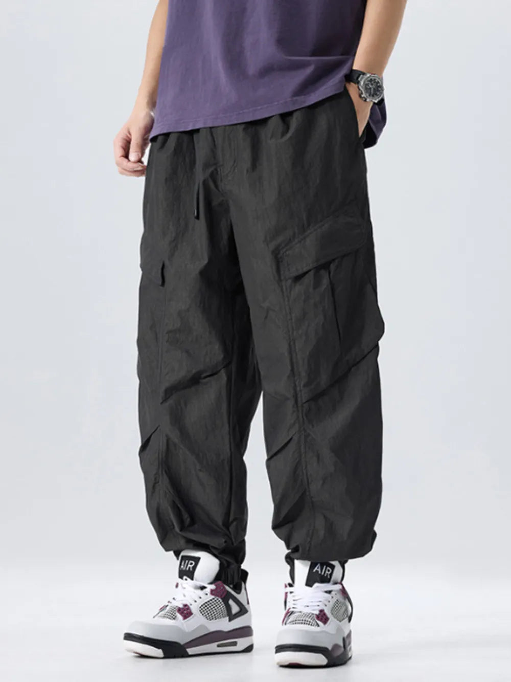 Black oversized cargo pants with adjustable drawstring waist and large side pockets.